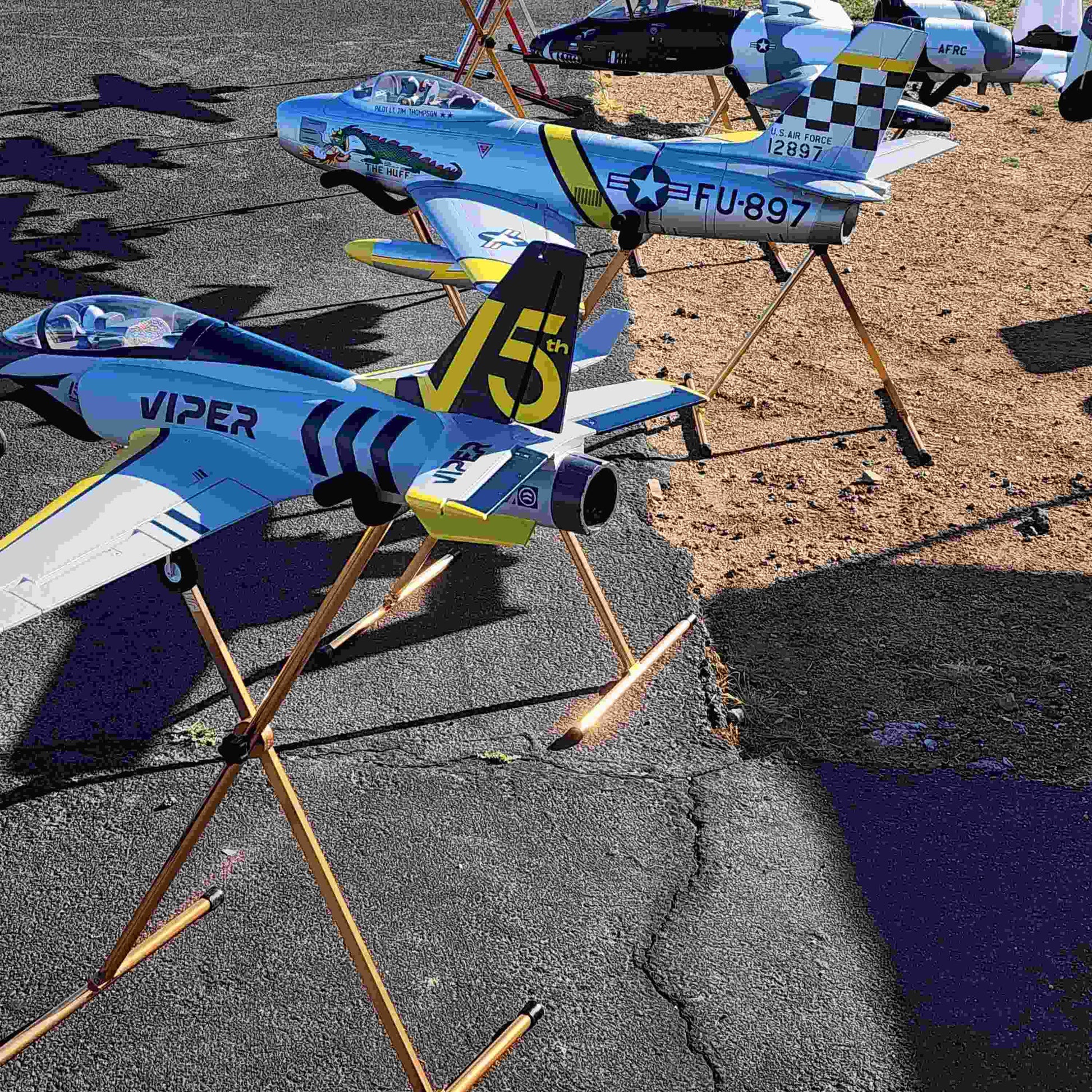 Multicolored RC airplanes on FMS Model Airplane Stand outdoors